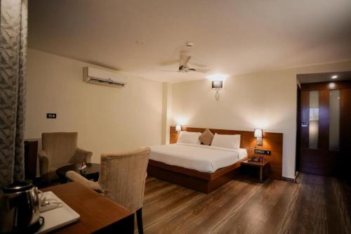 a hotel room with a bed and a desk and a table at Hotel New Indraprastha in Adūr