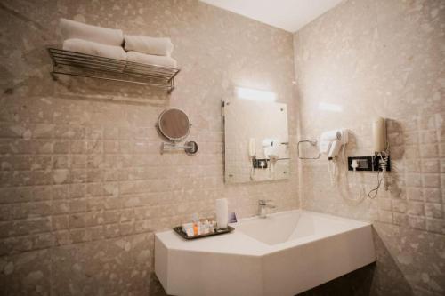 a bathroom with a white sink and a mirror at Hotel New Indraprastha in Adūr