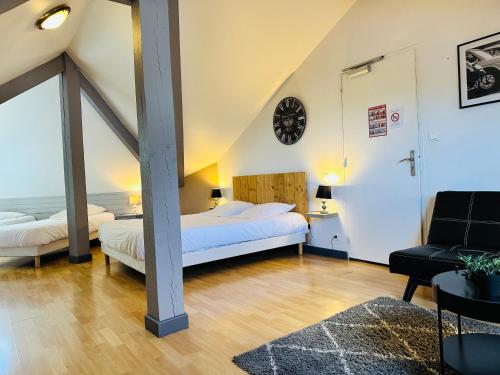 a attic bedroom with two beds and a clock on the wall at Logis Hôtel Restaurant Volcan Sancy in Nébouzat