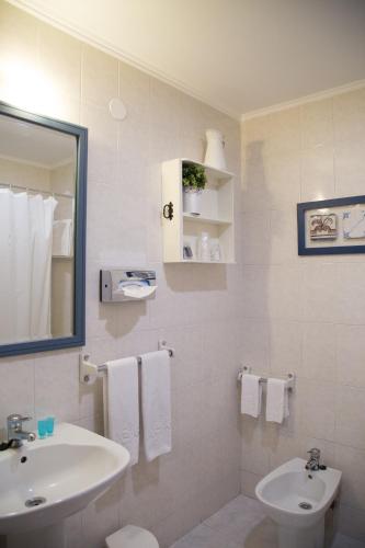 a white bathroom with a sink and a toilet at Hotel A.S. Lisboa in Lisbon