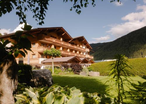 a large building with a green lawn in front of it at Hotel Brugger in Fulpmes