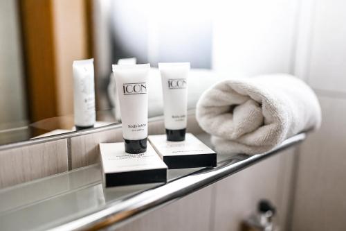 a bathroom counter with towels and moisturizers on a mirror at Hotel Vaka in Brno