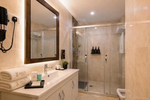a bathroom with a shower and a sink and a mirror at Jalo Hotel - Shashemene in Shashemenē