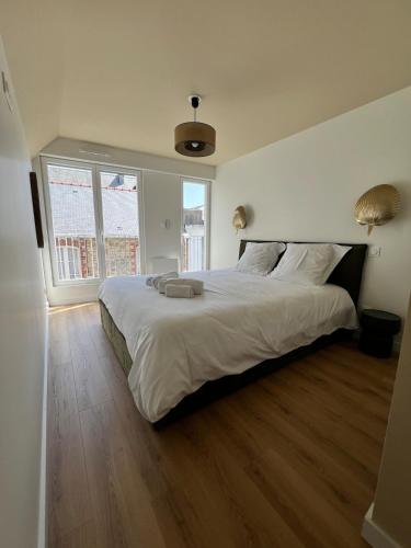 a bedroom with a large white bed and two windows at Maison Hyper-centre Dinard - Garage privé - 200 M plage in Dinard