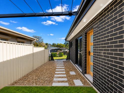 a walkway next to a brick building at Matildas Urban Escape 6-Min Station & Shops in Campbelltown South