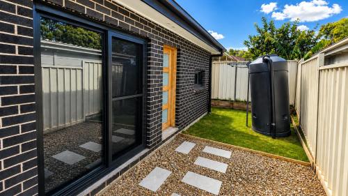 a house with a window and a air conditioner at Matildas Urban Escape 6-Min Station & Shops in Campbelltown South