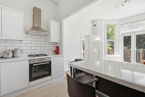 a white kitchen with a stove and a counter at Madeley Oak in Ealing