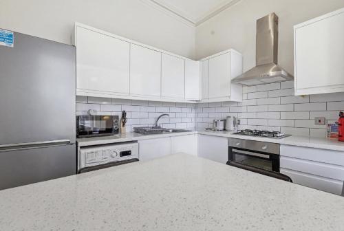 a white kitchen with white appliances and white cabinets at Madeley Oak in Ealing
