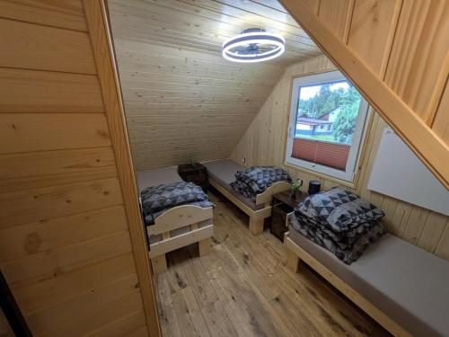 an attic room with two beds and a window at Domki Przydwórz in Przydwórz