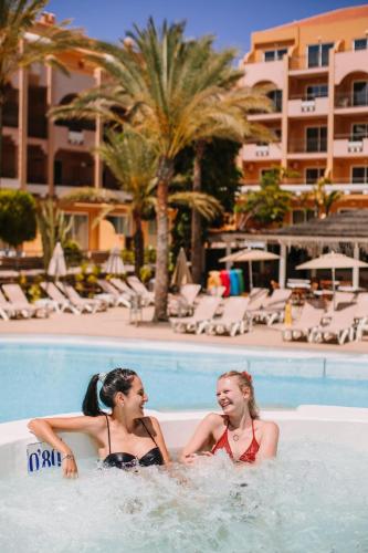 two girls sitting in a swimming pool at a hotel at Mirador Maspalomas by Dunas in Maspalomas