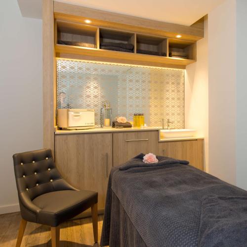 a bedroom with a bed and a chair and a counter at Belton Woods Hotel, Spa & Golf Resort in Grantham