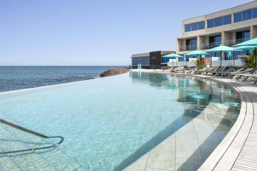 a large swimming pool next to the ocean at Barceló Praia Cape Verde in Praia