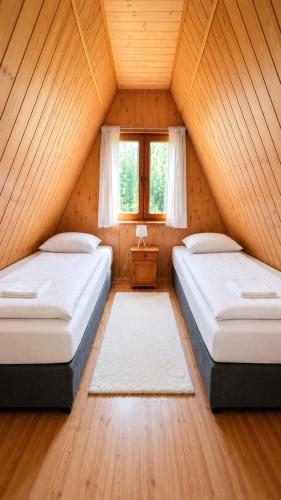 two beds in a attic room with a window at Domki Bieszczady Siedlisko Harenda in Czarna