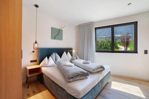 a bedroom with a bed with pillows and a window at Apartment Oberhaslerhof in Schenna