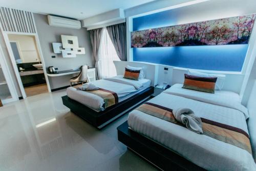 a bedroom with two beds and a blue wall at Mantra Varee Hotel in Khon Kaen
