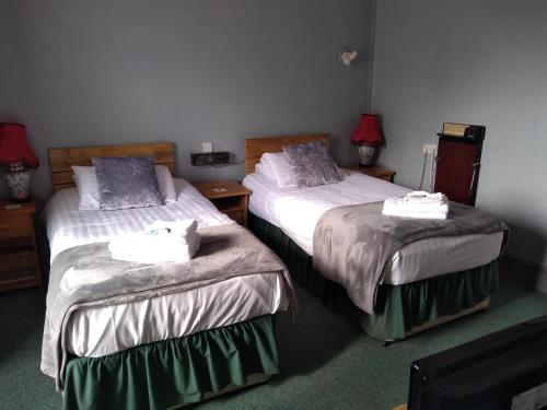 ein Hotelzimmer mit zwei Betten, auf denen Handtücher liegen in der Unterkunft Glendower Hotel in Goodwick