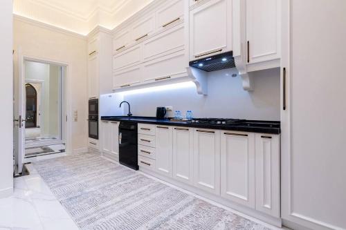a kitchen with white cabinets and a black counter top at Boulevard Residence Suite, 3 in Tashkent