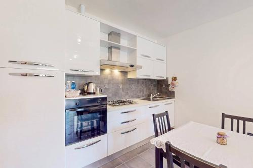 a kitchen with white cabinets and a table with chairs at [BuenRetiro] Giardino, box e bici a disposizione in Acqui Terme