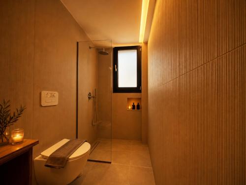 a bathroom with a toilet and a shower with a window at ELÉNAS slow living villa in Faliraki