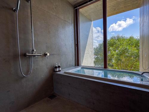 a bathroom with a bath tub with a window at 大木の宿 Shicari in Yomitan