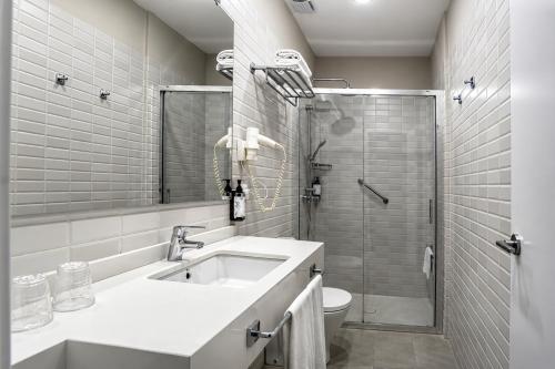 a white bathroom with a sink and a shower at Hotel Simon in Seville