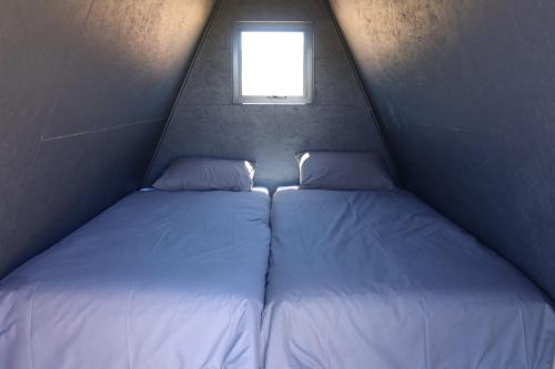 two beds in a small room with a window at Karoo 62 Escape - A-frame in Ladismith