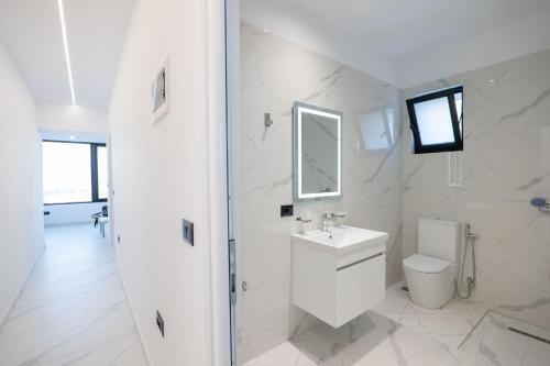 a white bathroom with a toilet and a sink at Lina's House in Sarandë