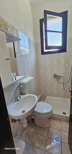ein Badezimmer mit Waschbecken, Toilette und Fenster in der Unterkunft Special Delight in Agios Ioannis