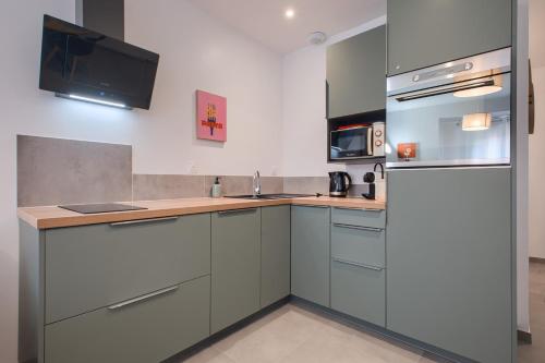 a kitchen with gray cabinets and a refrigerator at Le Cocon de Cossé - Wifi - 300m Centre in Cossé-le-Vivien