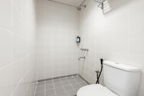 a white bathroom with a toilet and a shower at Amaris Hotel Pekanbaru in Pekanbaru