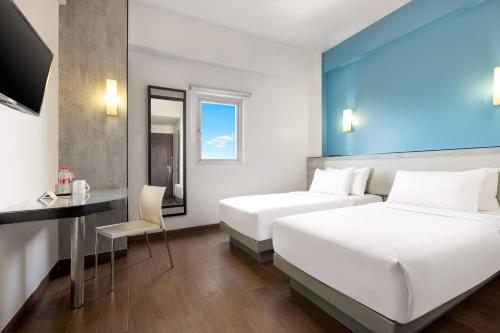 a hotel room with two beds and a desk at Amaris Hotel Pekanbaru in Pekanbaru