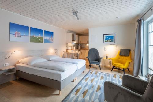a bedroom with a bed and a yellow chair at Nordsee-Apartments Hinrichsen in Husum