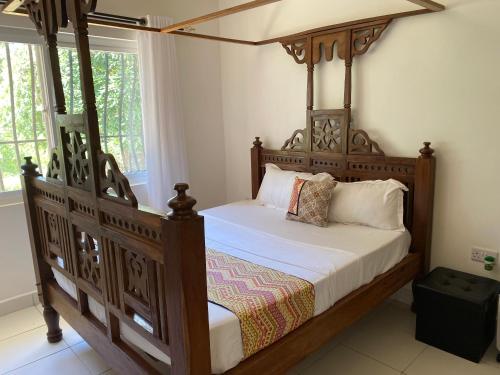 a bedroom with a wooden bed with a canopy at Nyumba Nzuri in Ukunda, Diani in Ukunda