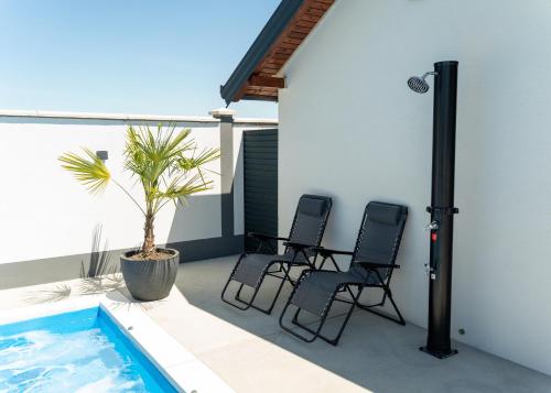 a patio with three chairs and a swimming pool at Villa Azure Sea in Bijeljina