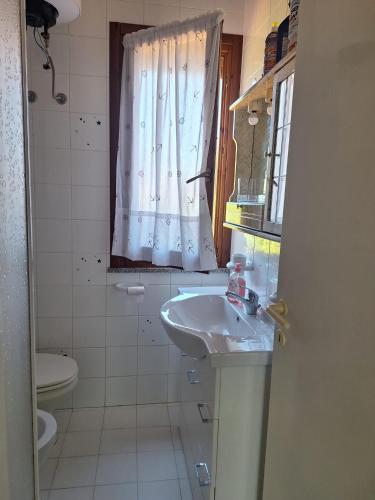 a bathroom with a sink and a toilet and a window at Villetta La Ginestra in Stintino