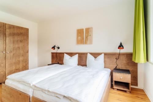 a bedroom with a large white bed with a wooden headboard at Bodeapartment 8 in Elend