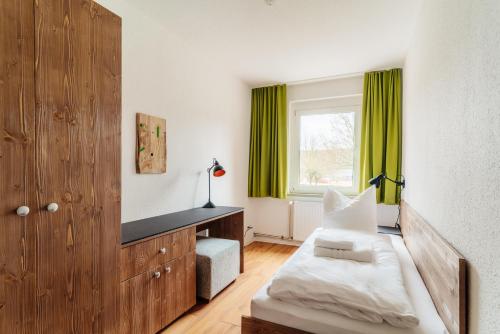 a bedroom with a bed and a window with green curtains at Bodeapartment 3 in Elend
