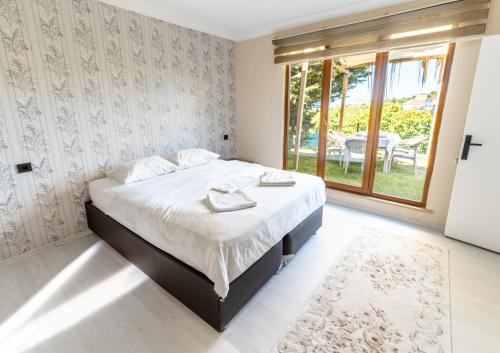a bedroom with a bed and a large window at Natural Villas Trabzon in Komera