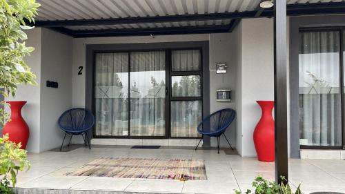 a porch with two blue chairs and two red vases at Sebeshong Guest House - Moletjie in Ga-Komape