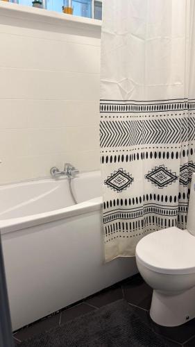 a bathroom with a toilet and a tub and a shower curtain at TEATRA Apartamenti in Liepāja