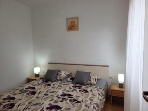 a bedroom with a bed with two night stands and two lamps at Apartman Perka in Valbandon
