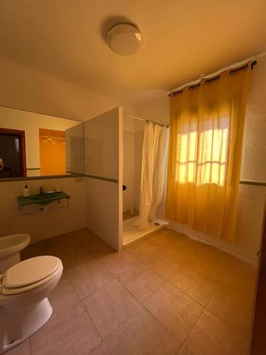 a bathroom with a toilet and a shower with a window at Marenga in El Rompido