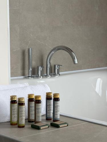 Vier Flaschen ätherischer Öle stehen neben einer Badewanne. in der Unterkunft Hotel Keto in Podgorica