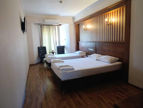 a hotel room with three beds and a window at Grand Center Boutique Hotel in Kyrenia