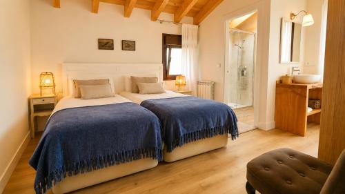 a bedroom with two beds and a bathroom with a sink at La Casina de San Pedro Ribadesella in Ribadesella