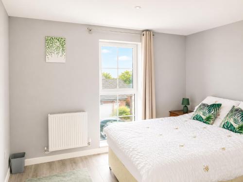 a white bedroom with a bed and a window at Dainty Curve in Kettering