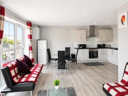 a living room with a couch and a kitchen at Dainty Curve in Kettering