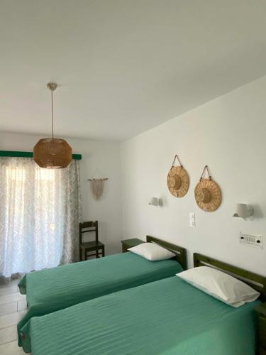 two beds in a bedroom with green sheets at Kapares Studios & Apartments in Agia Anna Naxos