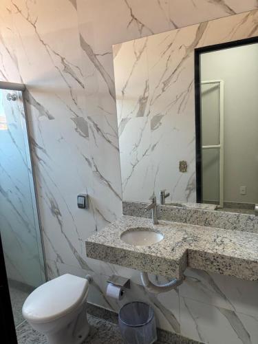 a bathroom with a toilet and a sink and a mirror at Diplomata Hotel in Sertãozinho