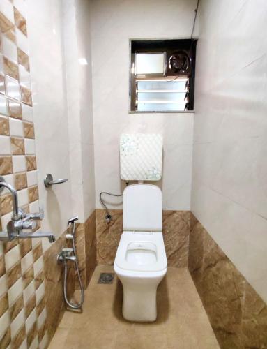 a bathroom with a toilet and a window at Hotel Sagar Residency in Panvel